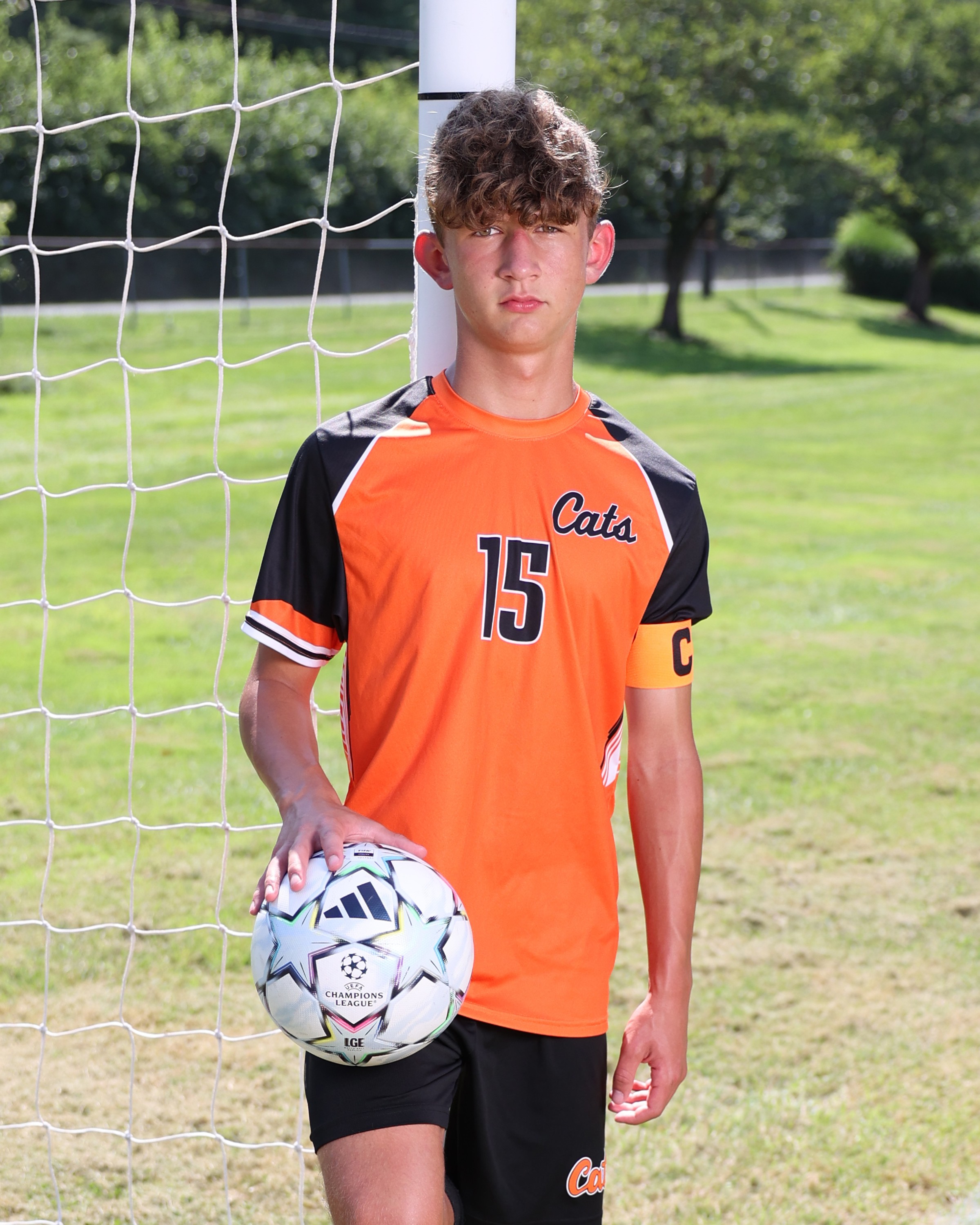 Middle school captain Gabe Daniels, #15, poses with a soccer ball in front of the goal.